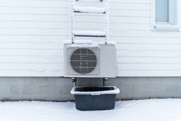 buitenunit van warmtepomp met sneeuw erop