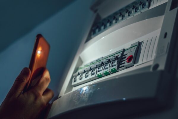 persoon met mobiel in hand bekijkt meterkast